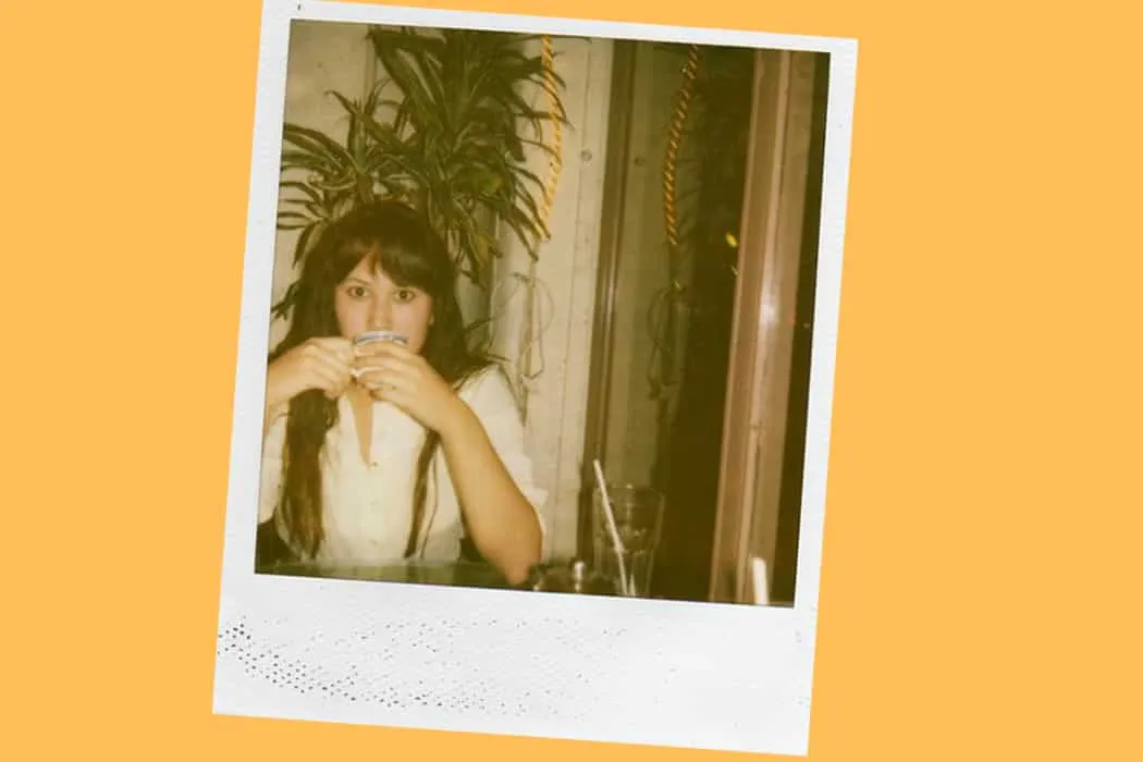 Young woman enjoying coffee at a cozy cafe, surrounded by indoor plants and warm lighting, creating an inviting atmosphere fo