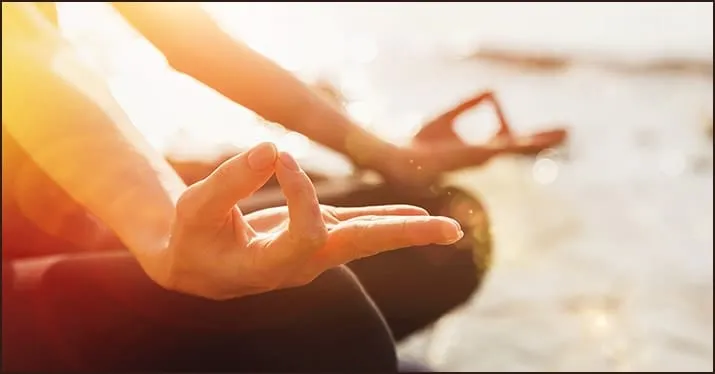 Silhouette of a person practicing yoga or meditation on the beach during sunset, focusing on mindfulness and wellness.