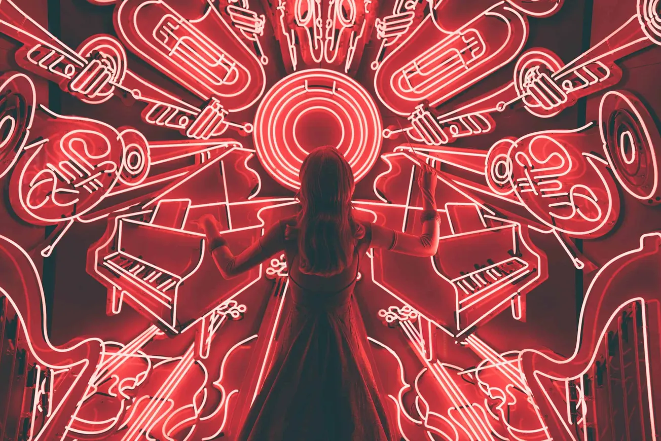 Bright neon musical instruments and notes wall art at Hypebot, showcasing vibrant concert and music industry visuals in red g