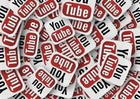 YouTube logo badges scattered in a pile, representing social media branding and digital content platforms for online video sh