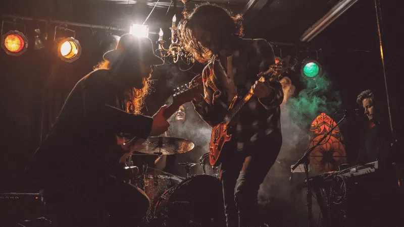Musicians playing guitars on stage during live concert with colorful stage lights, capturing energetic underground music perf