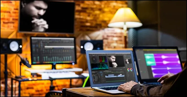 Creative music production studio with laptops, audio monitors, and editing software for digital music creation and sound engi