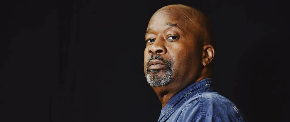 Powerful portrait of a confident African American man with a serious expression, wearing a denim jacket, against a dark backg
