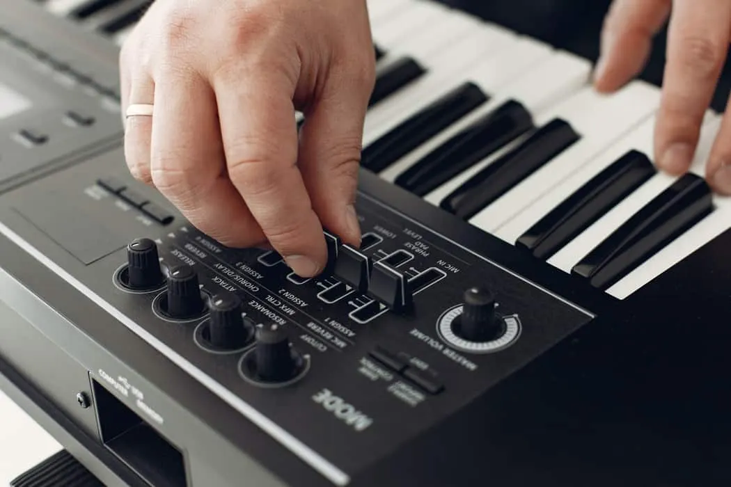 Synthesizer keyboard with hands adjusting sound controls, music production, electronic music, sound design, music technology.