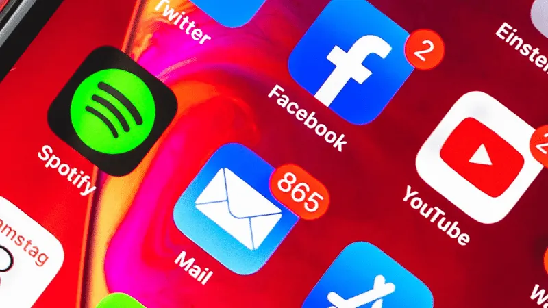 A colorful smartphone screen displaying social media app icons including Facebook, YouTube, Spotify, and email notifications,