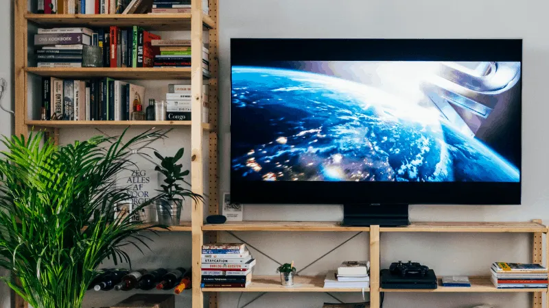 Earth from space displayed on a flat-screen TV in a modern living room, surrounded by bookshelves, plants, and media devices,