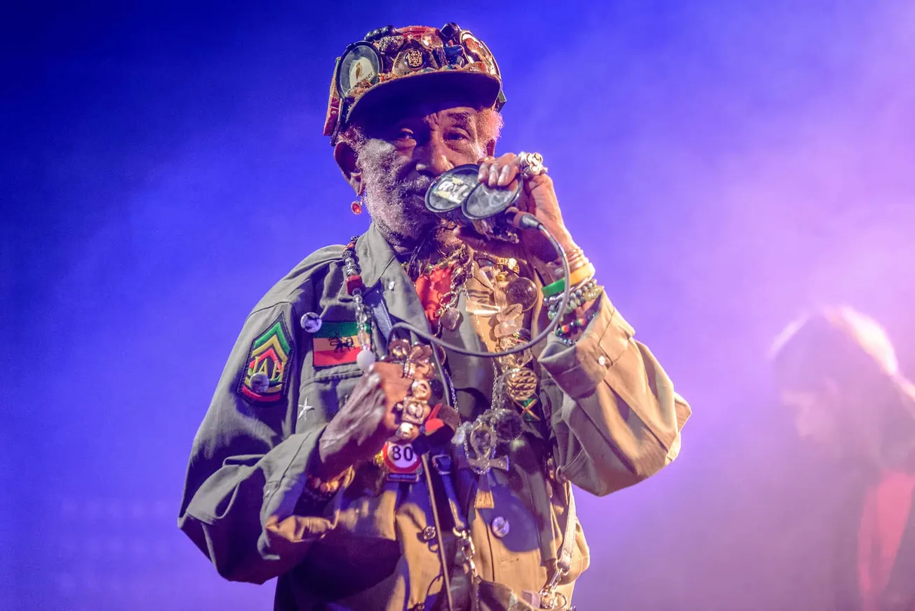 Colorful elderly musician performing on stage with vibrant lighting, wearing eclectic jewelry and accessories, showcasing jaz