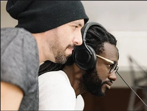Close-up of two male music producers working in a studio with headphones, focused on mixing or mastering audio, showcasing th