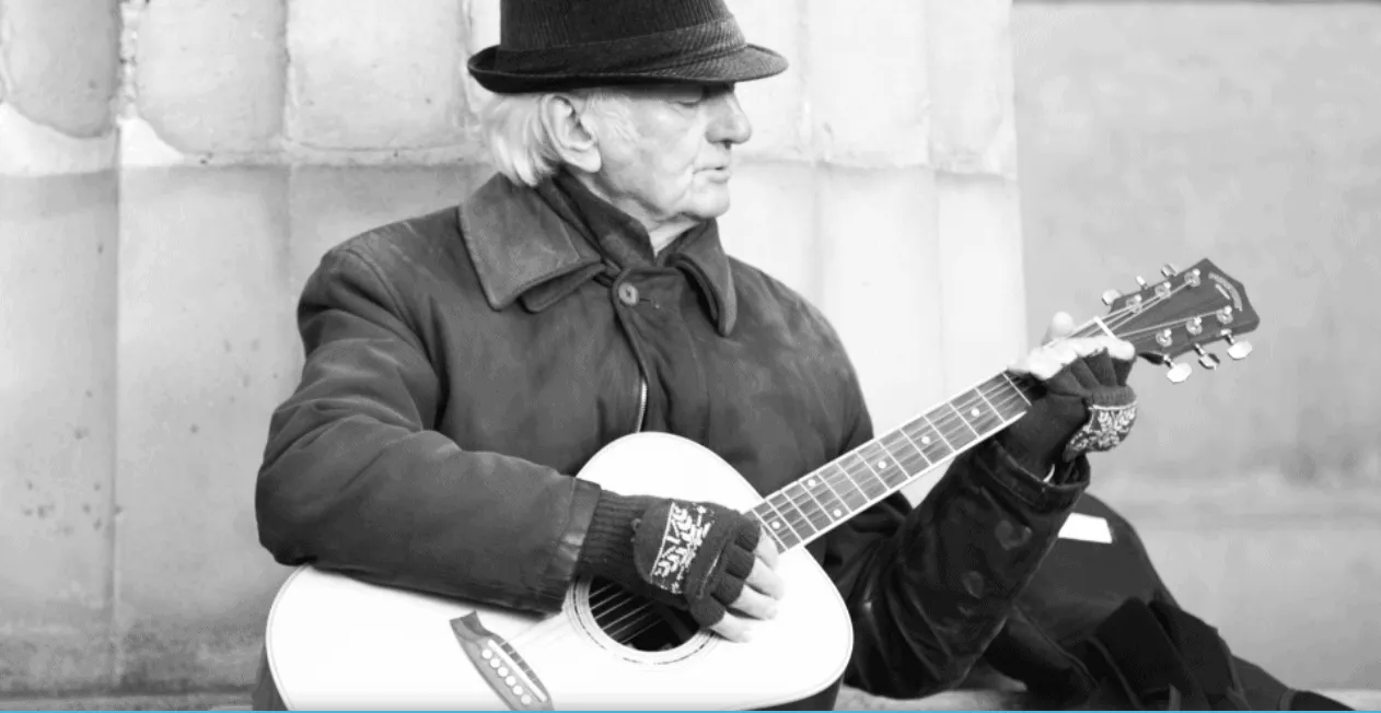 Elderly man playing acoustic guitar on street, black and white music performer street musician outdoor music art cultural sce