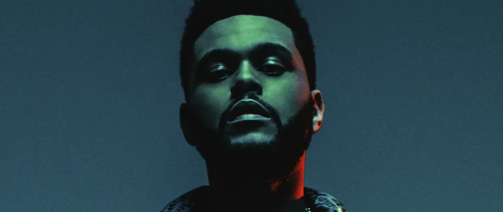 Bold male musician with a confident expression posing against a dark background with colorful lighting, emphasizing modernity