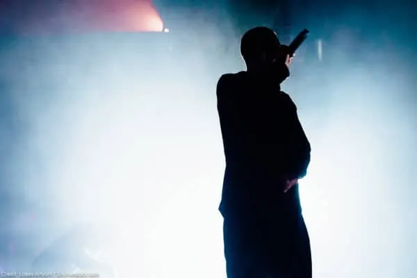 A silhouetted singer performing on stage with dramatic lighting and fog effects, highlighting live music and entertainment sc