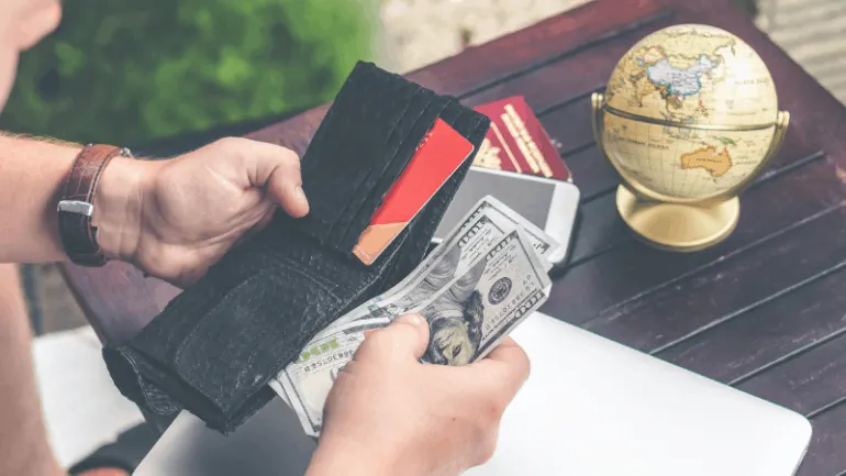 Wallet with cash, credit card, smartphone, and passport on wooden table, emphasizing travel, financial management, and digita