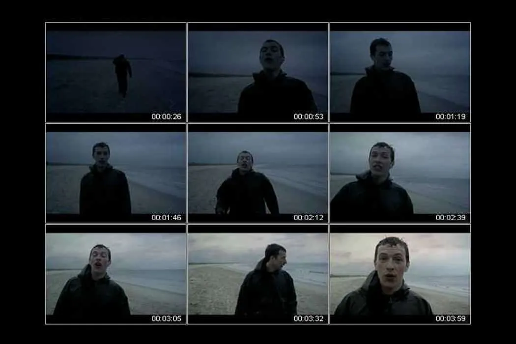 Beach scene with young man in dark clothing at dusk, moody ocean landscape, cinematic shots, emotional tone, tall and short s