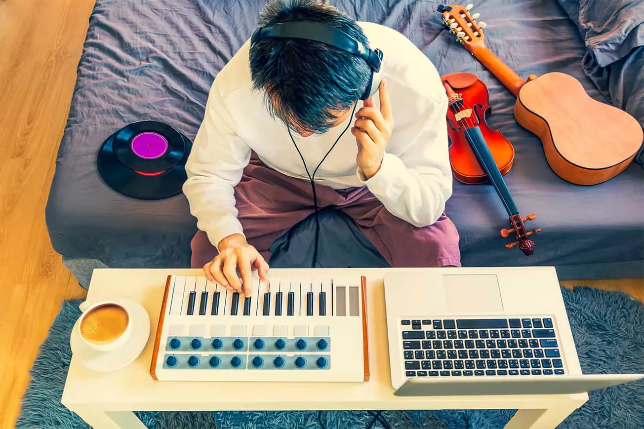 Creative musician recording music at home with keyboard, laptop, and musical instruments, representing music production, digi