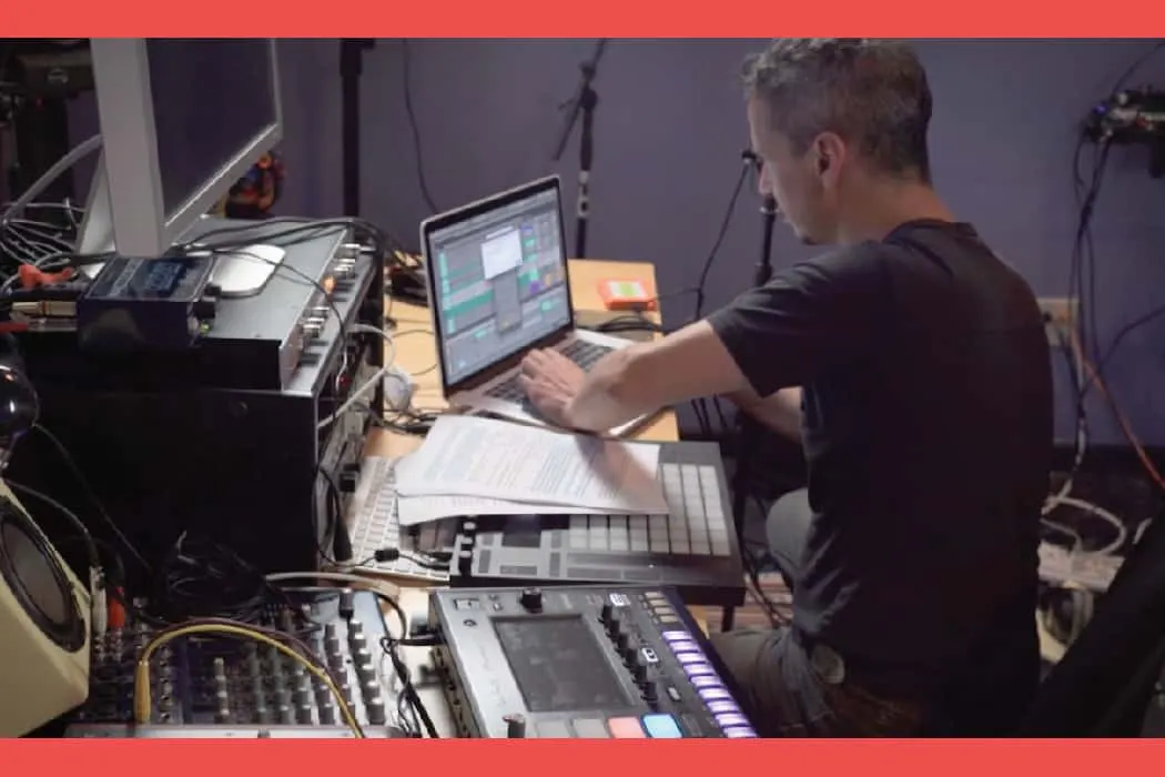 Music production studio with a producer working on electronic music using laptop and MIDI controllers at Hypebot website.