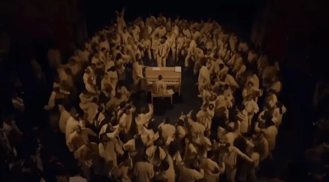 Aerial view of a live music event with a musician playing a piano surrounded by a large crowd of festival attendees, capturin