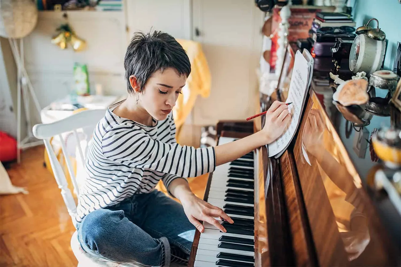Young woman practicing piano in cozy home setting, focusing on music and musical instrument.