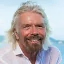 A smiling man with white hair and a beard enjoying a sunny outdoor setting, representing positivity and well-being.