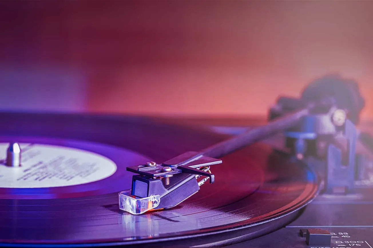 Vintage turntable playing vinyl record with colorful ambient lighting, music industry technology, DJ equipment, and audio mix