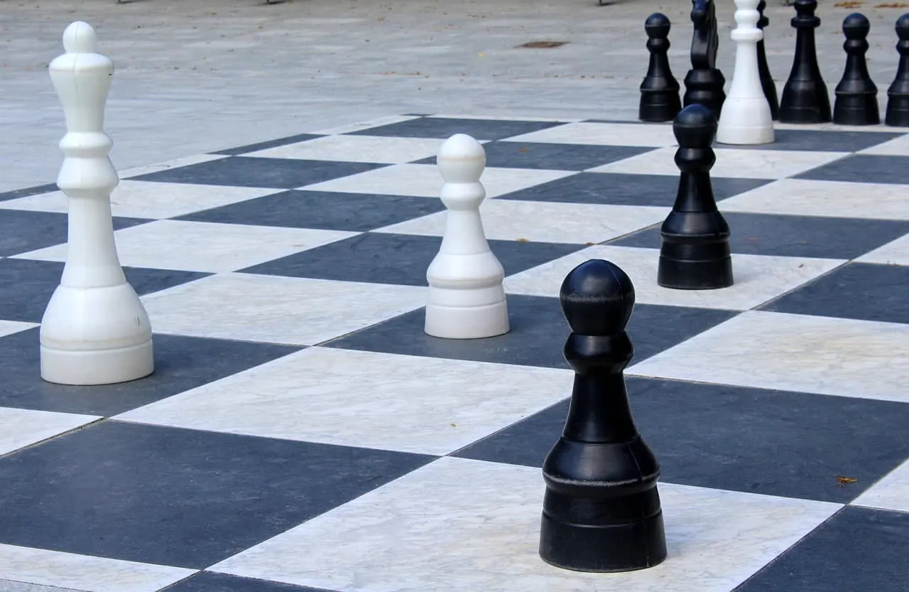 Black and white chess pawns on a checkered board, illustrating strategic gameplay and competitive thinking. Perfect for artic