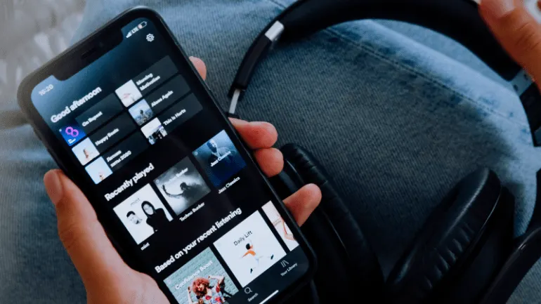 Streaming music on a smartphone with headphones, emphasizing digital music platforms and modern music listening technology.
