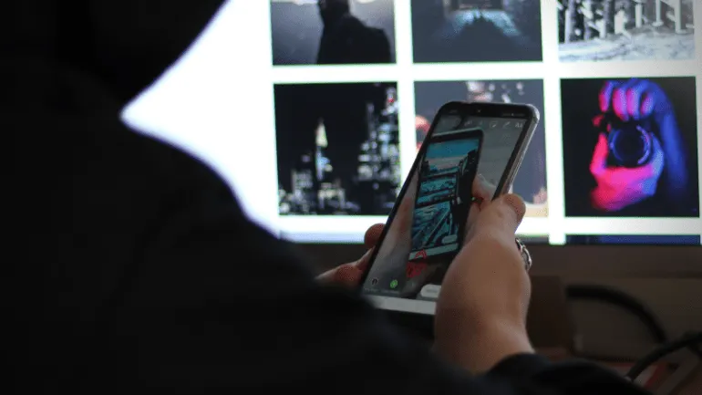Viewing and editing photos on a smartphone with a computer screen displaying various images in the background, capturing digi