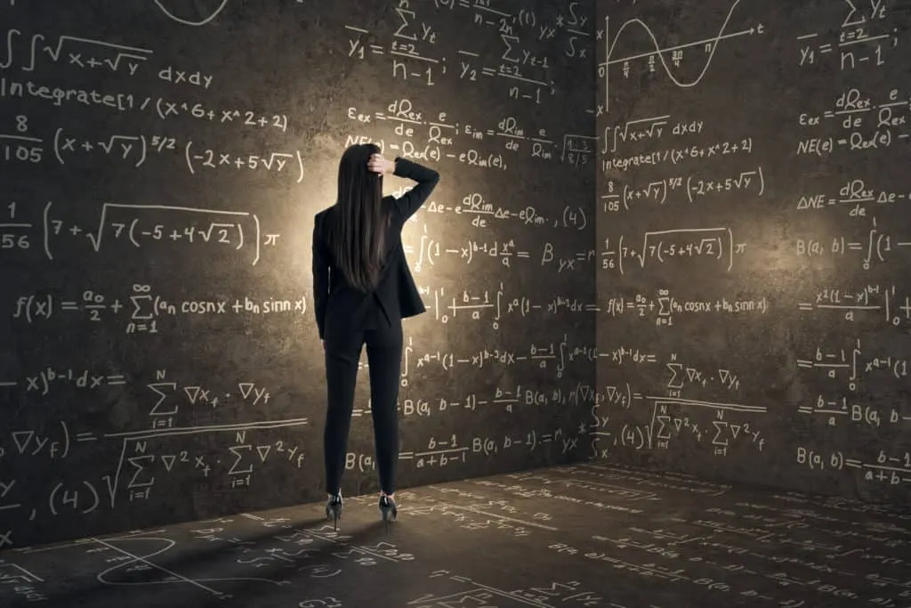 Complex mathematical equations written on a chalkboard with a woman in business attire analyzing data in a modern classroom.
