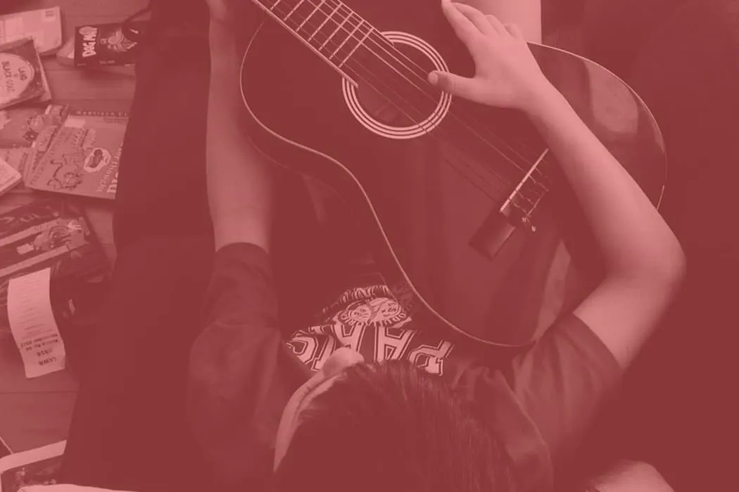 Acoustic guitar player practicing music at home, surrounded by music books and supplies, creating a cozy and artistic musical