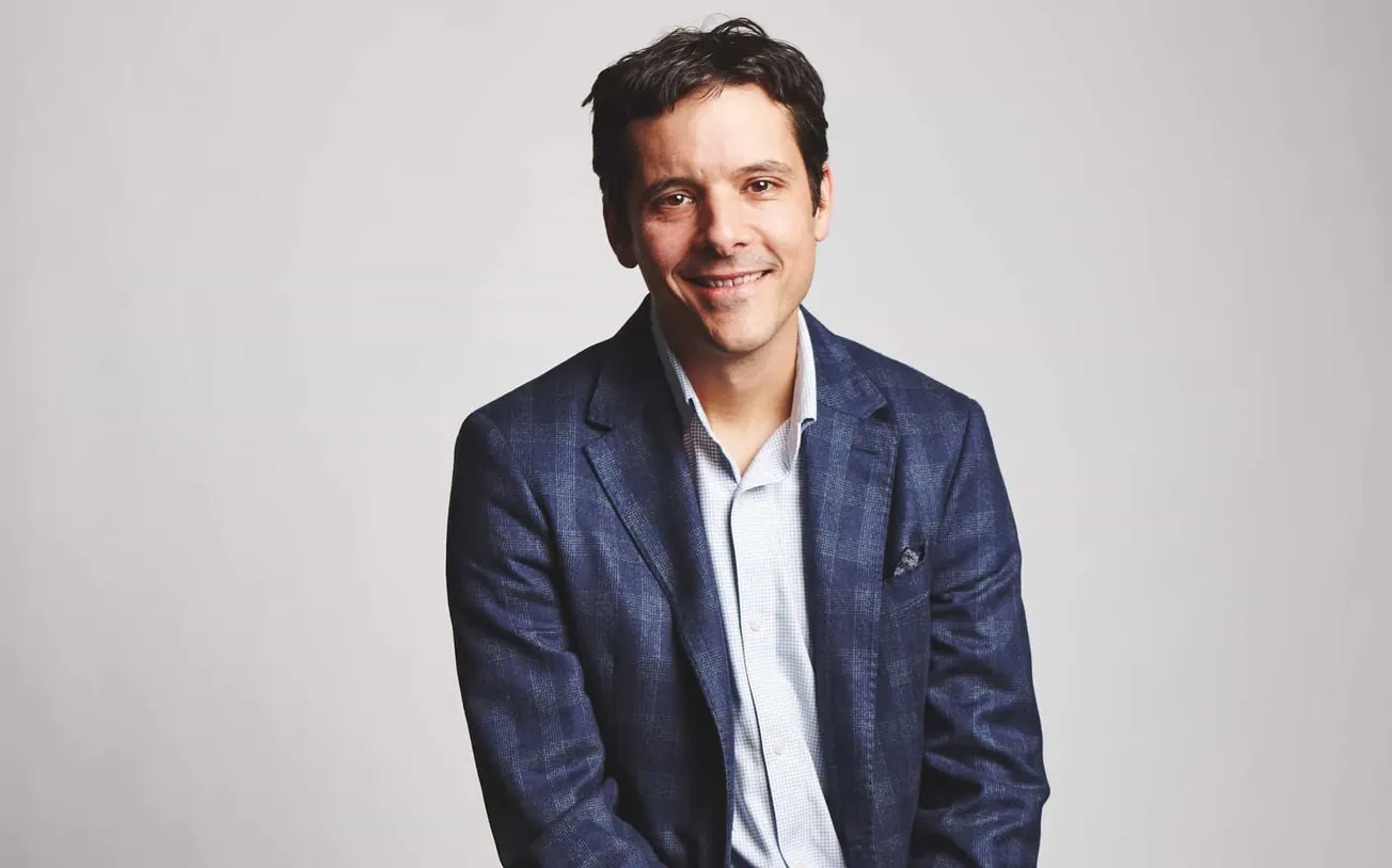 Professional man in a blue blazer smiling, representing music industry expert, influencer, or entrepreneur, with a clean back