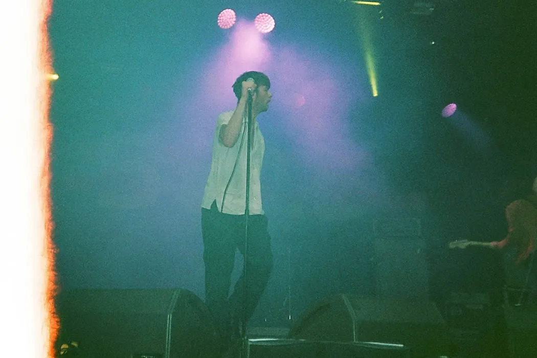 Male singer performing at a concert with colorful stage lights.