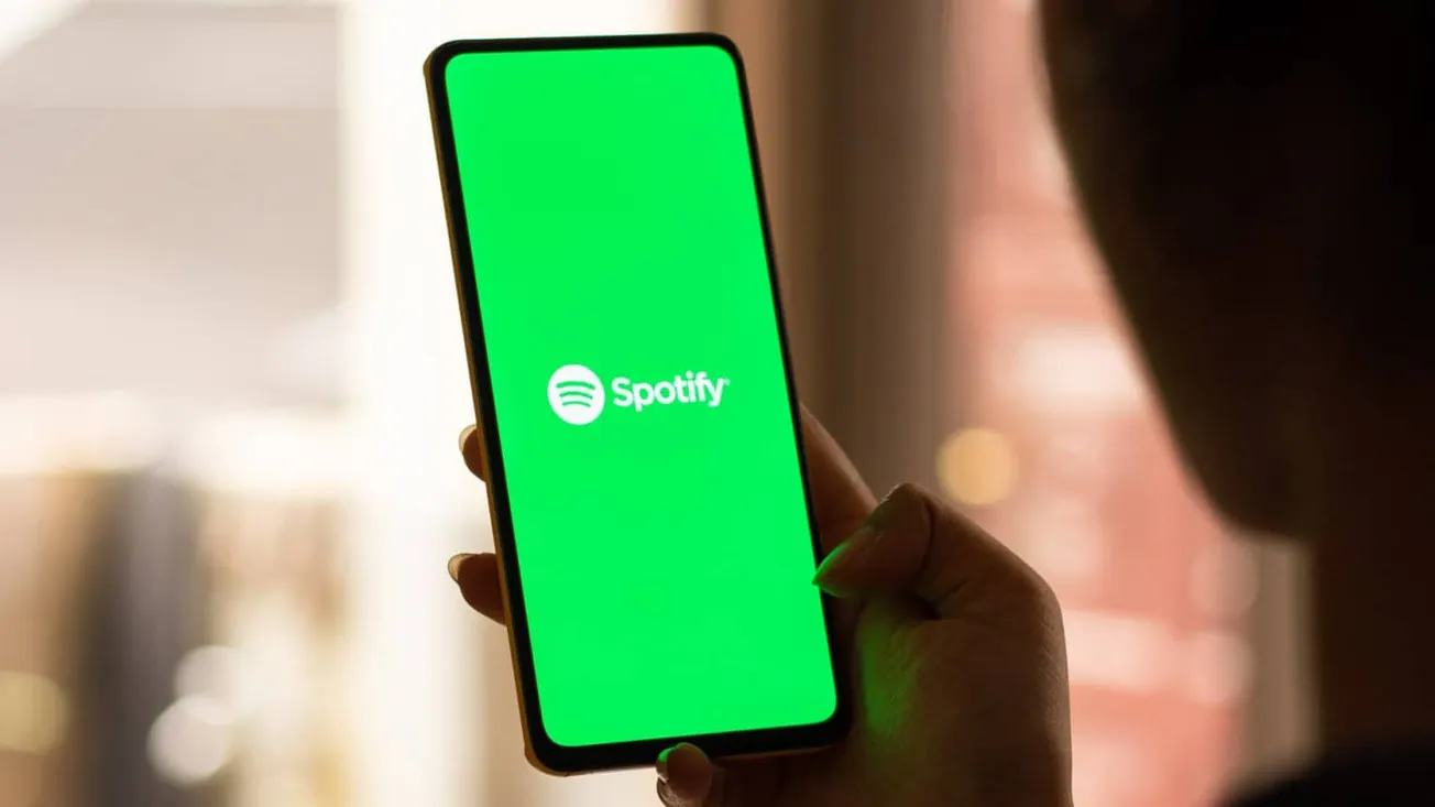 Spotify music app on smartphone screen, digital music streaming, user holding phone with spotify logo, modern tech, entertain