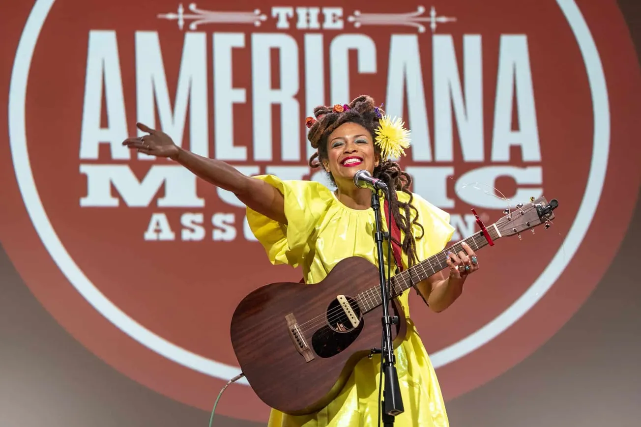Bright female musician performing live with guitar at Americana Music Association event, showcasing vibrant stage presence an