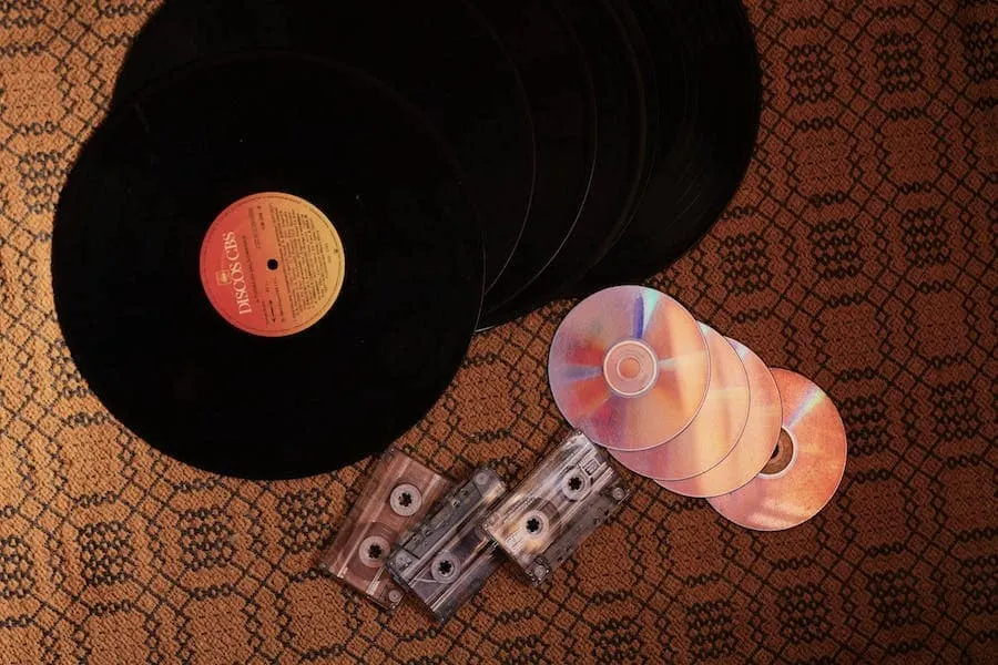 Vintage vinyl records and cassette tapes on patterned carpet, representing music collection and digital transition, suitable