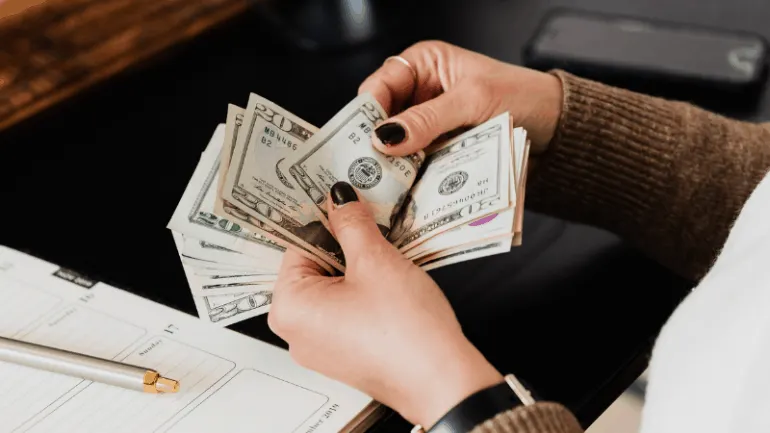 $20, $50, and $100 bills being held in hands, representing cash and financial transactions.