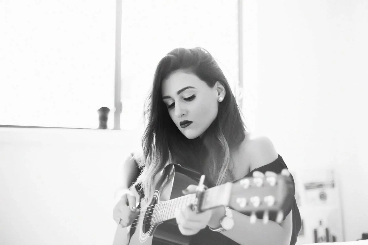 Young woman playing acoustic guitar in black and white studio photo music artist female musician talent musician artist creat