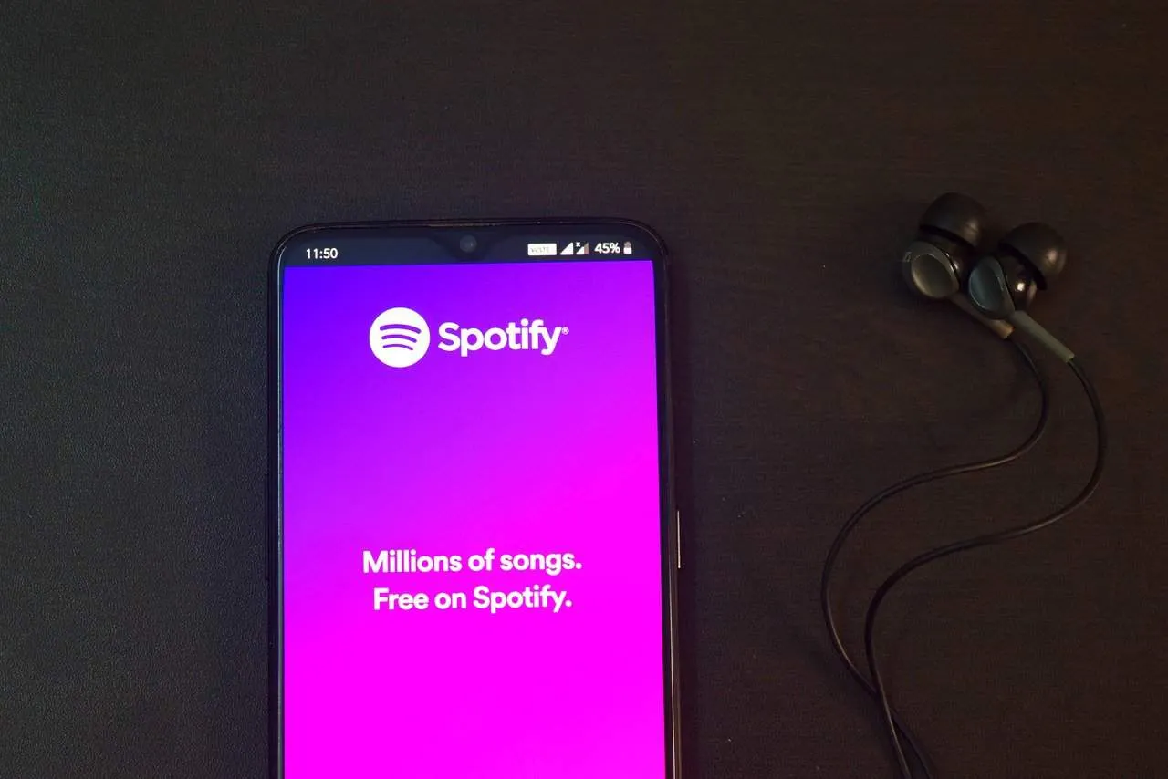 Spotify music app on smartphone with earphones, promoting music streaming service.