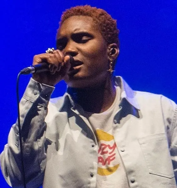 Vocalist performing on stage with a microphone under vibrant blue lighting, capturing a live music moment and showcasing pass