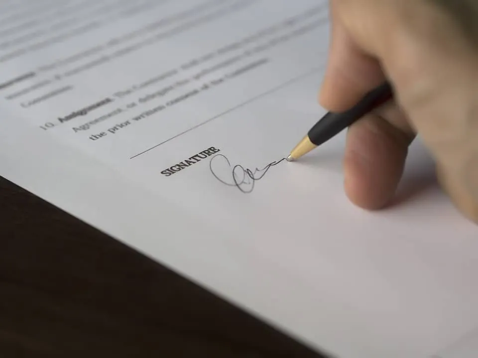 Legal document signing with a pen on paper, close-up of signature process.