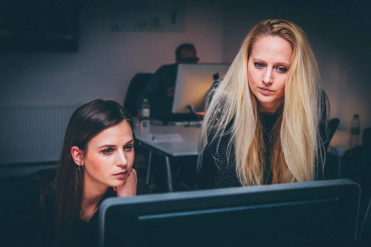 People working on a computer at an office, collaboration, women focused on digital project, professional team, modern workpla