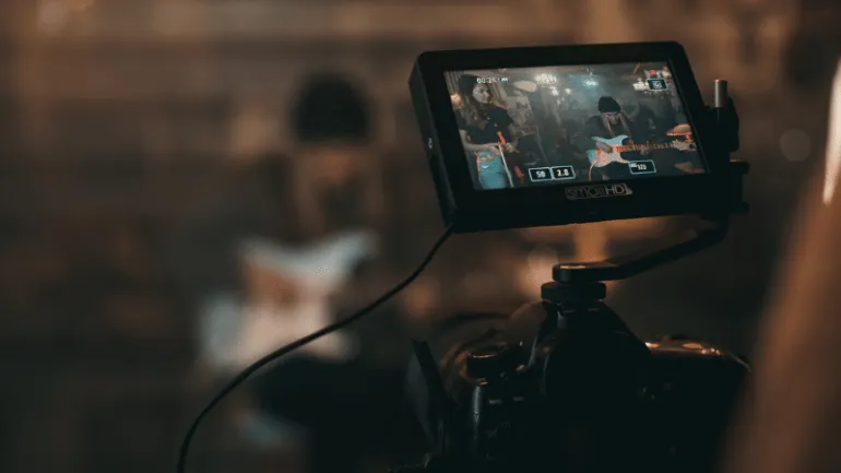 Professional music video recording setup with camera capturing live band performance in a studio. Advanced filming equipment