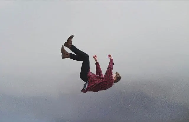 A person falling upside down against a cloudy sky, symbolizing chaos or loss of control.