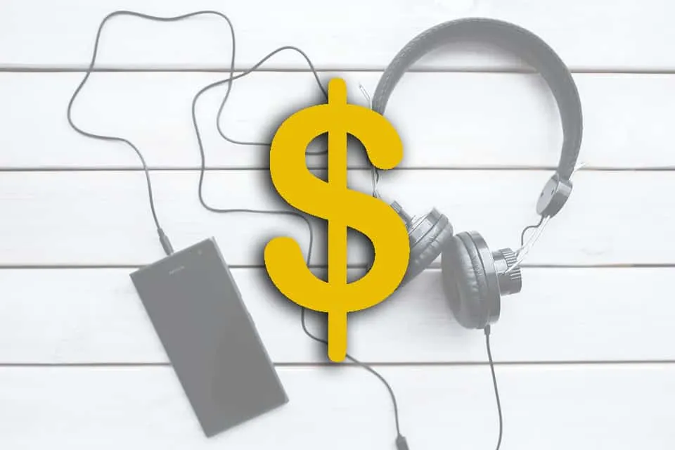 $ dollar sign with headphones and portable speaker on white wooden background, representing music monetization, digital music