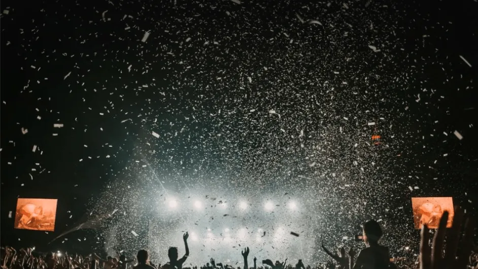 Colorful concert crowd celebrating with confetti at night, vibrant music event, lively atmosphere, music festival, concert, a