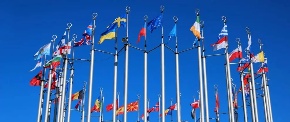 Colorful international flags flying against a bright blue sky, representing global music markets, multicultural collaboration
