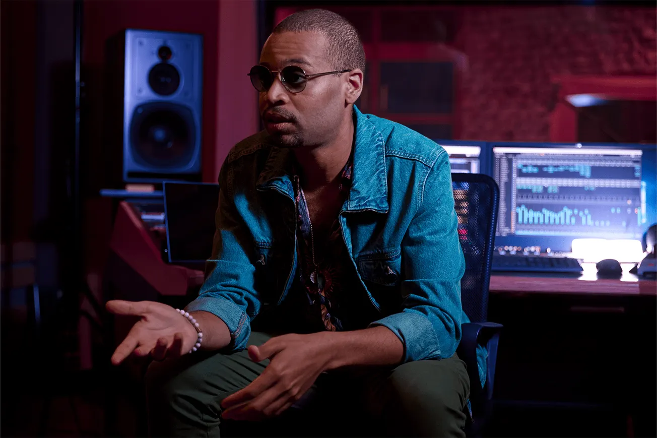 Professional music producer working in a modern recording studio with mixing console, computer monitors, and studio speakers