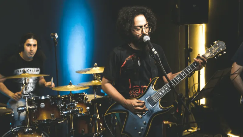 Energetic live band performing on stage with a guitarist and drummer, showcasing vibrant lighting and music equipment, captur