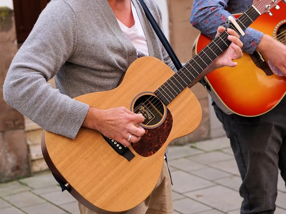 Acoustic guitar being played by a musician outdoors at a street performance musical event vibrant music scene music marketing