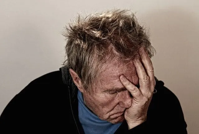 Overwhelmed man holding his head in frustration, depicting stress or worry.