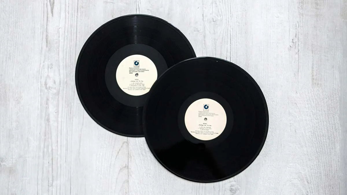 Vintage black vinyl records on a light wooden surface, ideal for music collectibles and retro music themes.