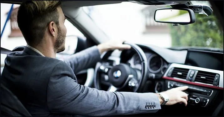 Driving a modern luxury car with a focus on in-car technology and interior design, showcasing an executive traveling or commu